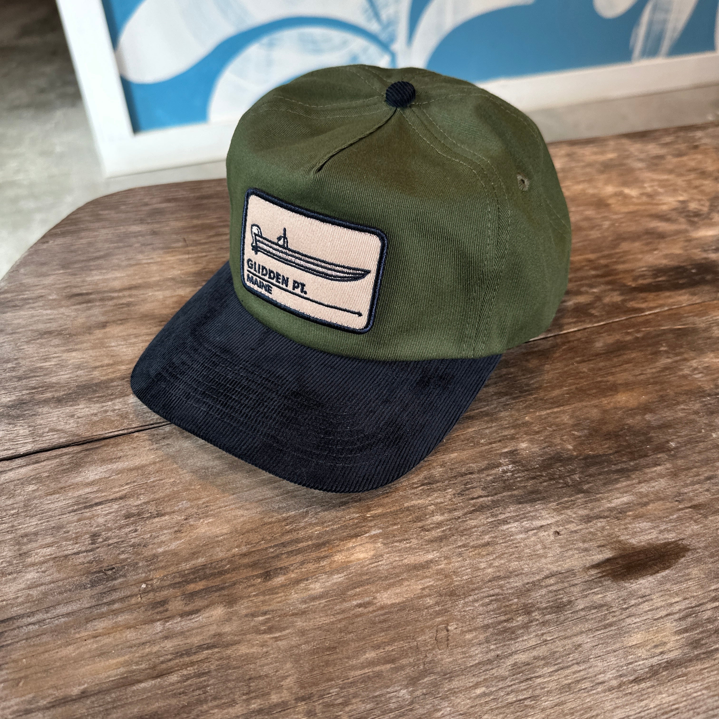 Green and black cap with a patch on a wooden surface