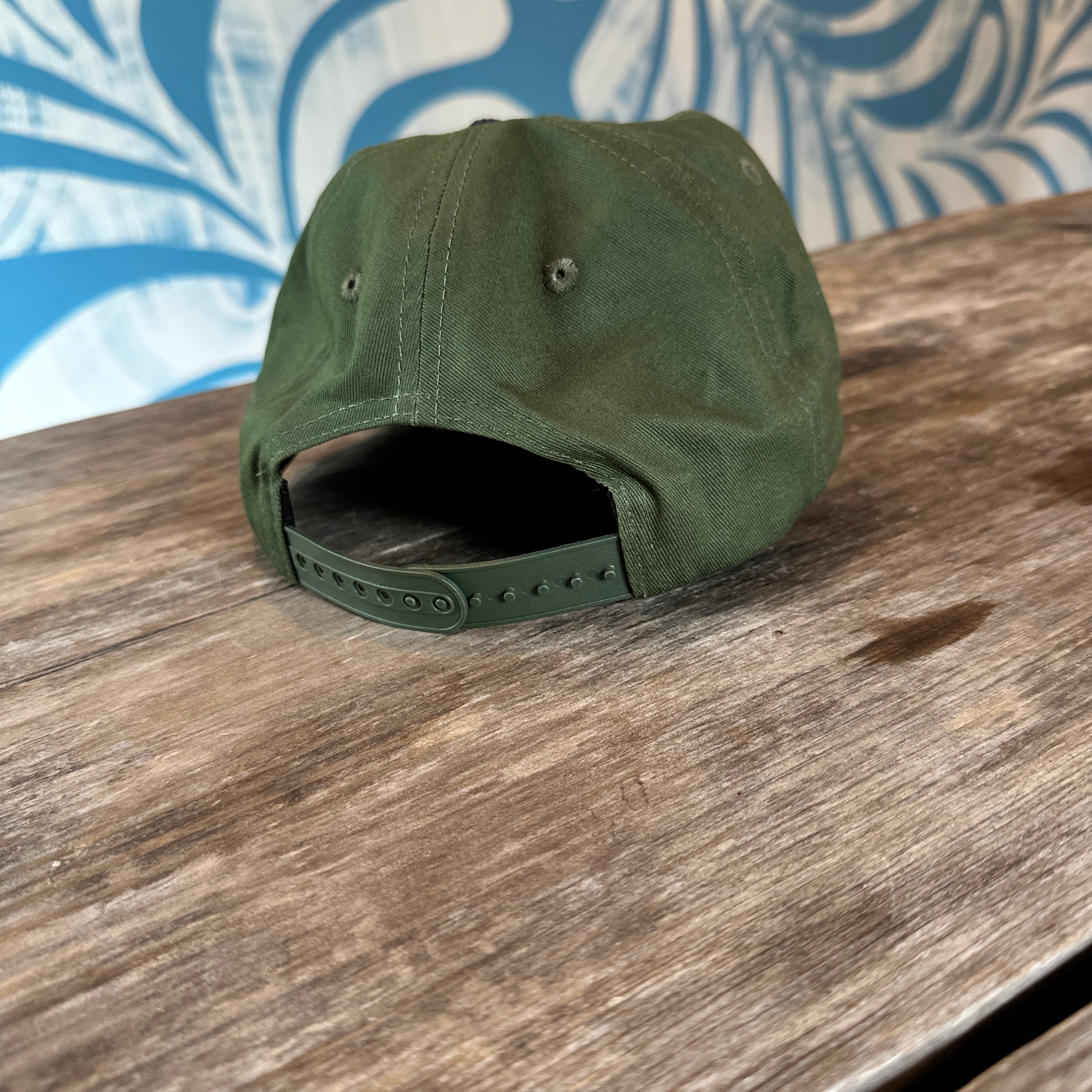 Green cap on a wooden surface with a blue and white patterned fabric background