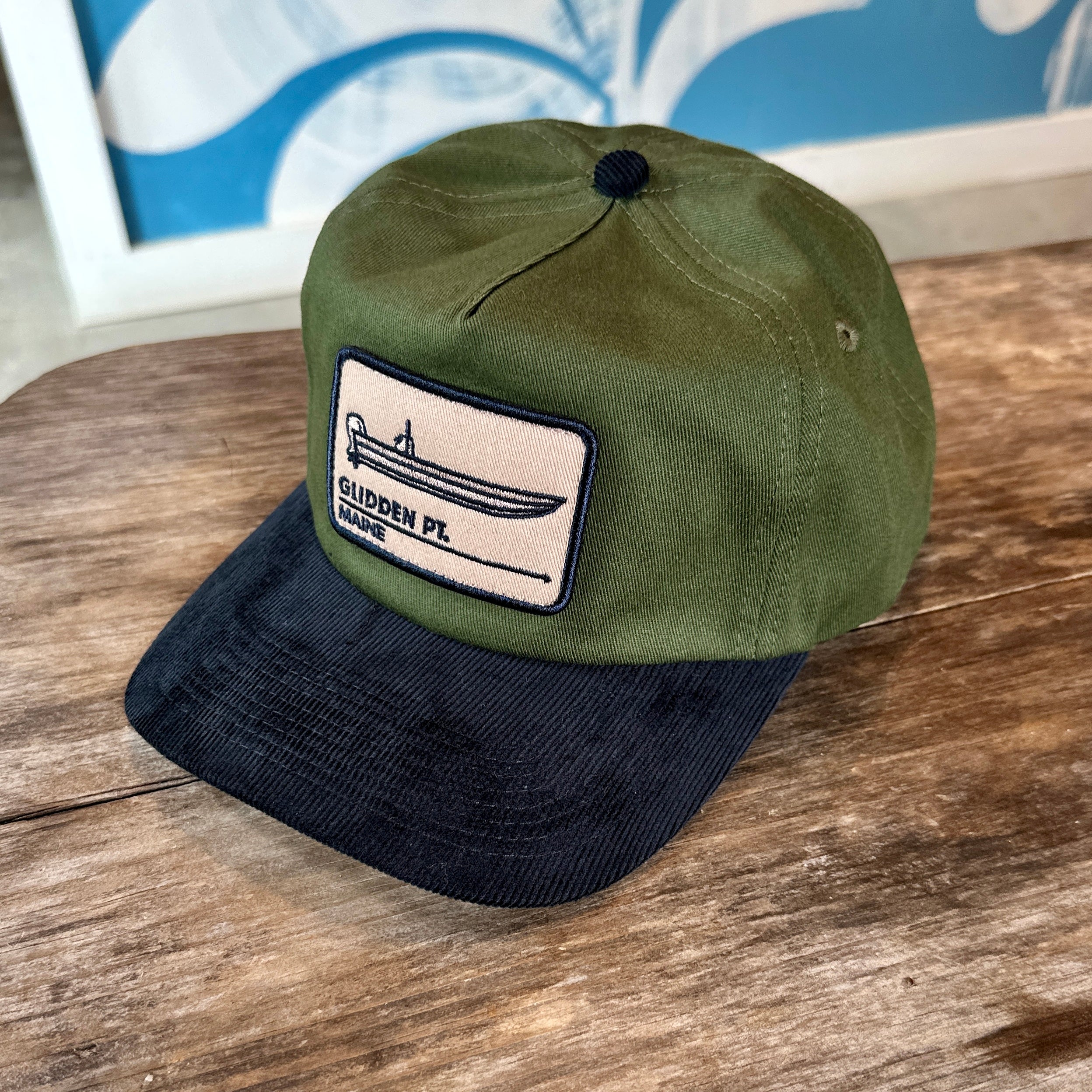 Green and black cap with a patch on a wooden surface