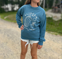 Person wearing a blue sweatshirt with a graphic design outdoors