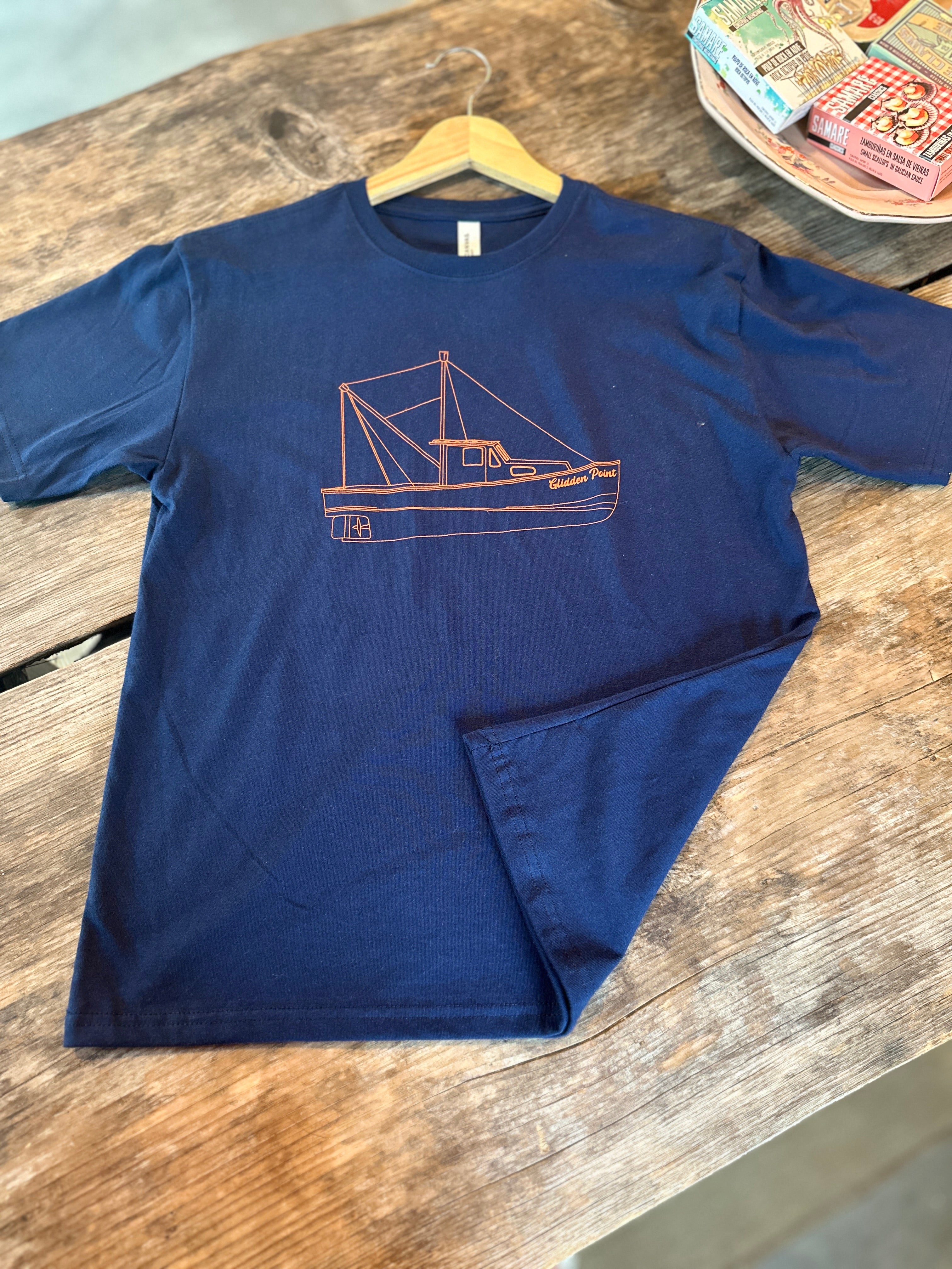 Navy blue t-shirt with a red boat design on a wooden surface