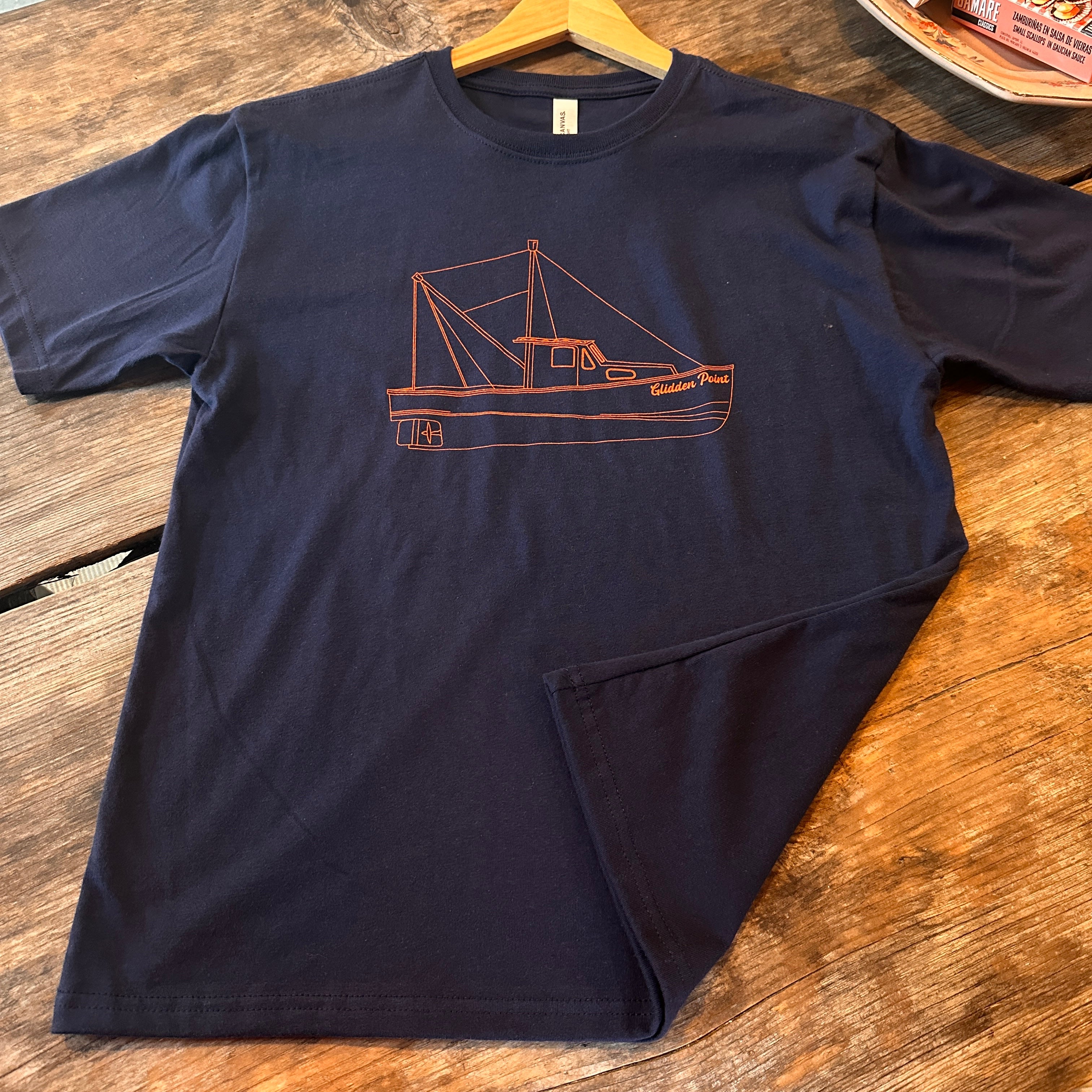 Navy blue t-shirt with a red graphic of a boat on a wooden surface