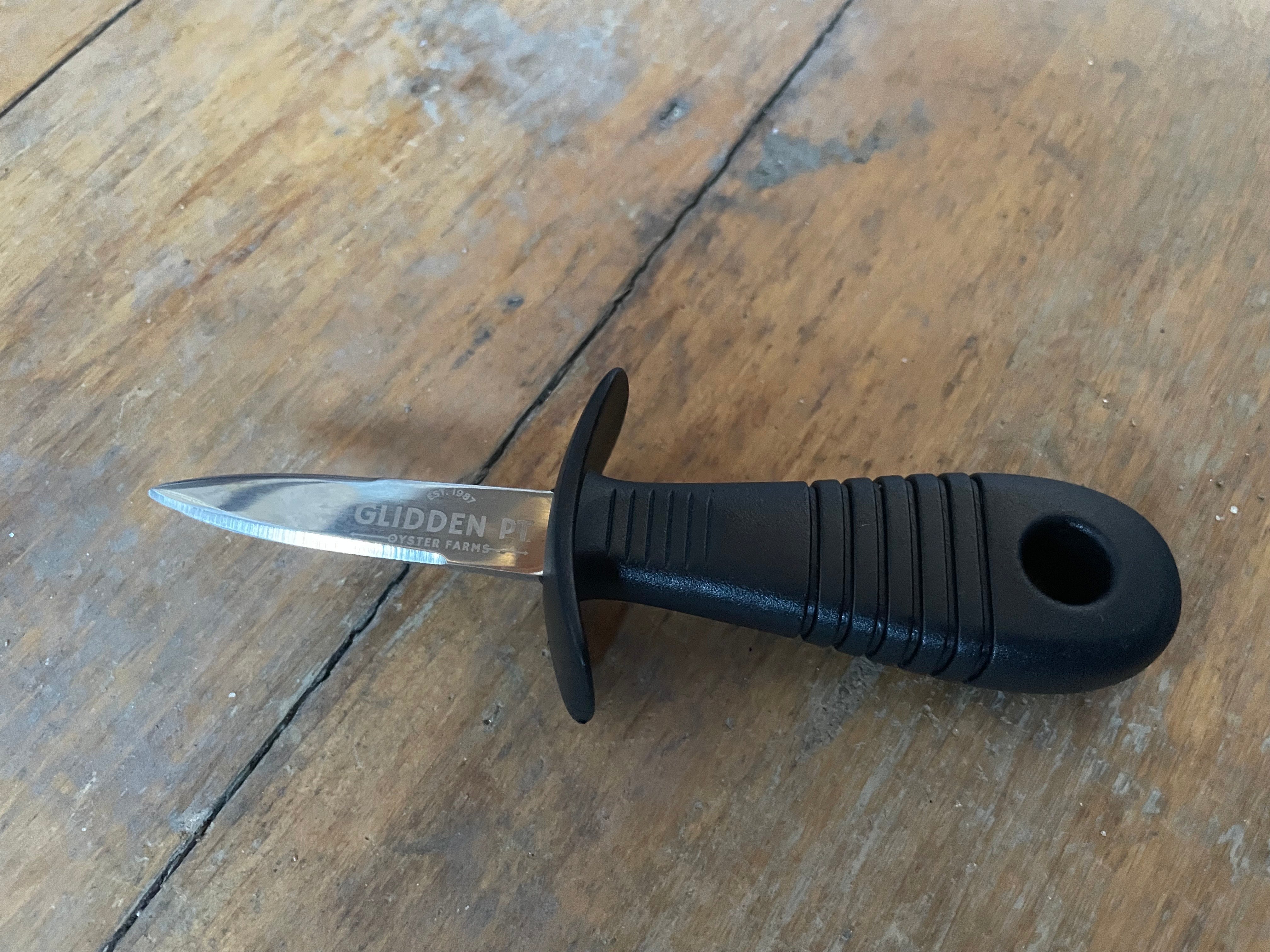 Black-handled knife with a metallic blade on a wooden surface